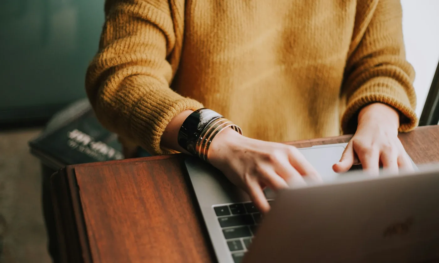 A person using a laptop at a wooden table