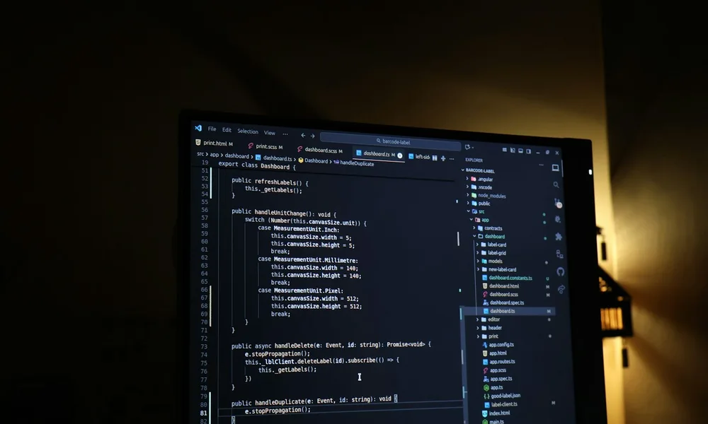 A web developer’s monitor with a dark code editor and warm lighting